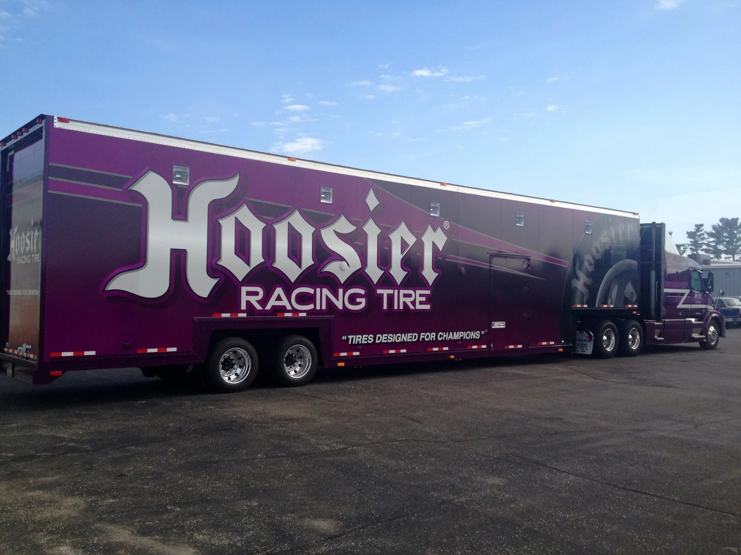 A Hoosier Racing Tire trailer with large purple and white branded graphics